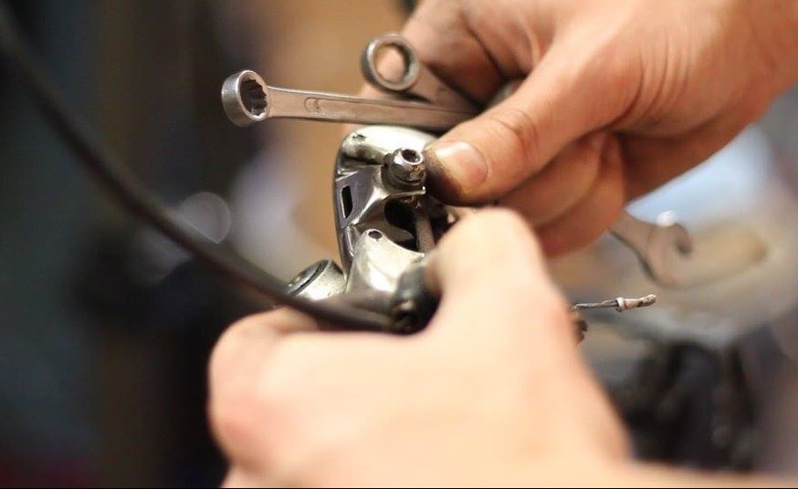 hands-on learning, fiddling with a rear derailleur at a bike maintenance workshop